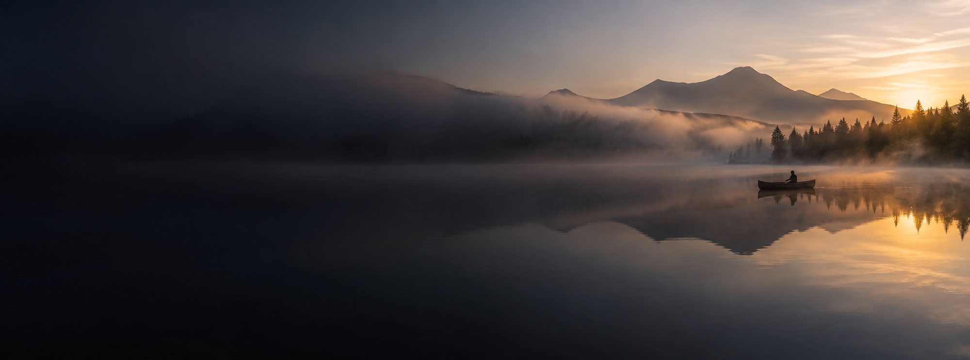 A single canoe on a still mountain lake at dawn